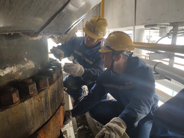 4月6日，機械修造部檢修二部張振華、盧超逸在檢修平臺處，進行4號氣化爐破渣機下降管短節(jié)法蘭螺栓的拆卸工作。.jpg