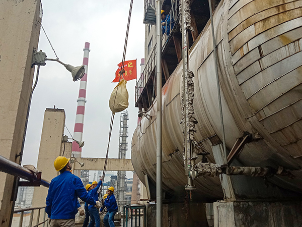 5月10日中午，在動力車間三期工藝除氧器地面，黨員突擊隊(duì)隊(duì)員用滑輪往工藝除氧器平臺運(yùn)送鋼絲網(wǎng)，用以纏繞新填料.jpg